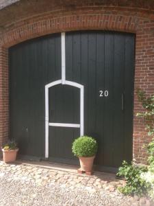 a green garage door with a brick wall at Hoheluft am Wittensee Apt 2 in Groß Wittensee