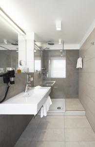 a bathroom with a large white sink and mirrors at Hotel Hiller in Abstatt in Abstatt