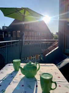 een tafel met twee groene theekopjes en een paraplu bij Ferienloft Am Ziegenmarkt Schwerin - ABC369 in Schwerin