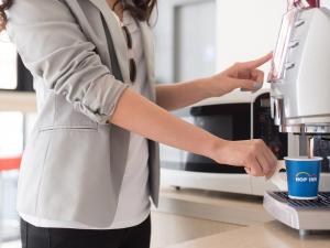 eine Frau, die mit einer Kaffeemaschine in einer Küche steht in der Unterkunft Hop Inn Ayutthaya in Phra Nakhon Si Ayutthaya