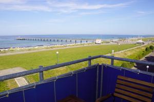 een blauw hek met een bank en de oceaan bij Pier 33 in Schönberger Strand