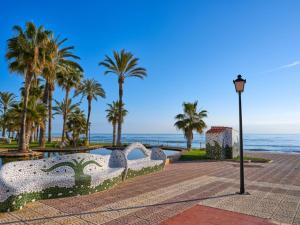 una luz de la calle junto al océano con palmeras en Apartamentos Terrazas al Mar 3000, en Oropesa del Mar