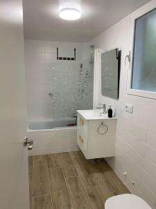 een witte badkamer met een wastafel en een bad bij Precioso piso nuevo en 1ª línea pantano SJuan4P in San Martín de Valdeiglesias