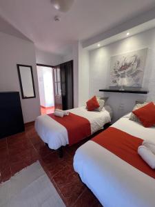 ロス・クリスティアーノスにあるApartamentos Funchalのベッド2台(赤と白のシーツ付)が備わる客室です。