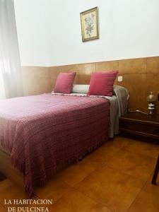 1 dormitorio con 1 cama grande con almohadas rosas en Habitacion de los molinos, en Mota del Cuervo