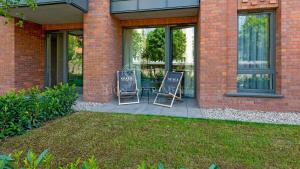 2 chaises assises sur une terrasse en face d'un bâtiment dans l'établissement Lion Apartments - SCALA City Center Cube Premium, à Gdańsk