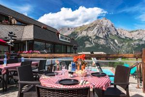 een tafel en stoelen met uitzicht op een berg bij Mountainhotel Saint Roch in Puy-Saint-Vincent