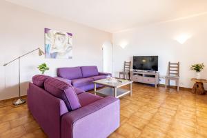 sala de estar con sofá púrpura y TV en Villa Dreams, en Son Bou