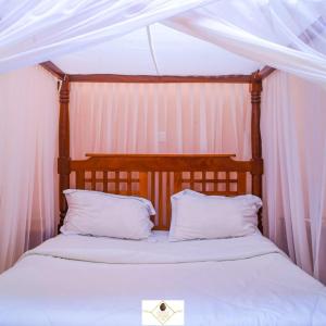 een hemelbed met witte lakens en kussens bij Holale Hotel in Moyale