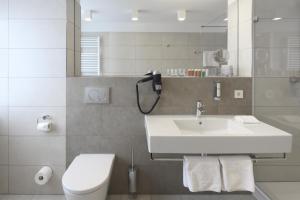 a white bathroom with a sink and a toilet at Hotel Hiller in Abstatt in Abstatt