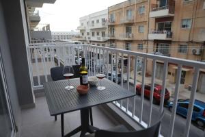 een tafel met een fles wijn en twee glazen op een balkon bij Spacious 3 bedroom apartment near bus terminus in St Paul's Bay