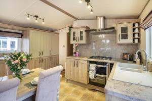 a kitchen with wooden cabinets and a table with a sink at QUEEN V - Luxury Caravan - 2Bed - Seton Sands in Port Seton