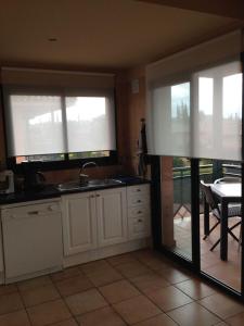 cocina con fregadero, 2 ventanas y mesa en Duplex Torremirona Resort, en Navata