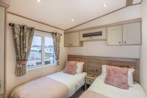 2 Betten in einem kleinen Zimmer mit Fenster in der Unterkunft QUEEN V - Luxury Caravan - 2Bed - Seton Sands in Port Seton