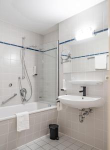 La salle de bains est pourvue d'une baignoire, d'un lavabo et d'une douche. dans l'établissement Hotel Goldener Hirsch, à Kaufbeuren