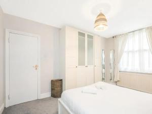 a white bedroom with a white bed and a window at Pass The Keys Basement Hideaway near Acton Main Line Your Peaceful Escape with London at Your Fingertips in London