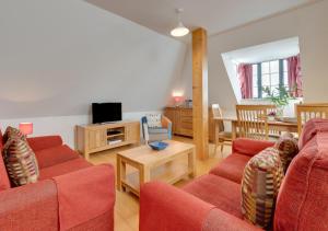 a living room with two red couches and a television at Flat 9 Broadleys in Swanage