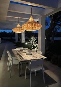 una mesa de madera con sillas y 2 lámparas de araña en Villa Gabriella, en Leuca