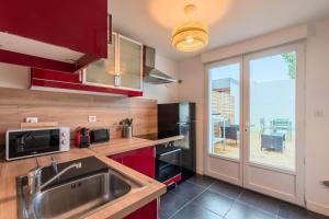 een keuken met rode kasten, een wastafel en een raam bij 3 bedroom house with terrace, near Lille in Marcq-en-Baroeul