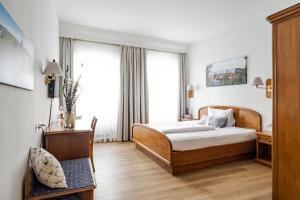 une chambre d'hôtel avec un lit et une chaise dans l'établissement Hotel Goldener Hirsch, à Kaufbeuren