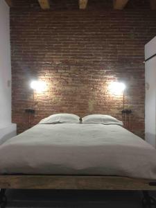 a bed with two lights on a brick wall at Cosy & Bright Apartment Near Ramblas in Barcelona