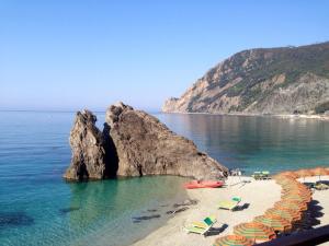 a beach with chairs and umbrellas on the water at Albergo Degli Amici in Monterosso al Mare