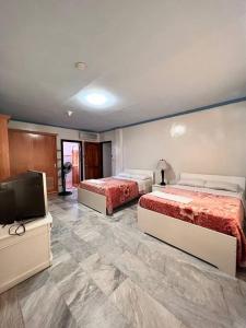 a room with two beds and a flat screen tv at Panglao Cove Resort_Main House in Dauis +5 photos