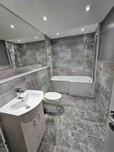 a bathroom with a sink and a toilet and a tub at Murrayfield Stadium Basement - 3 Bed 3 Bath in Edinburgh