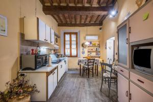 ブオンコンヴェントにあるLa Casa Gialla di Buonconventoのキッチン(白いキャビネット、テーブル、椅子付)