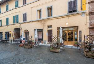 a building with chairs and tables in front of a store at La Casa Gialla di Buonconvento in Buonconvento