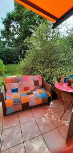 eine farbenfrohe Couch auf einer Terrasse neben einem Tisch in der Unterkunft Chambres d'hôtes Les Chênes in Acigné