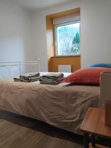 um quarto com uma cama com uma almofada vermelha e uma janela em La Grillère em Conliège