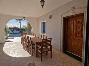 a dining room with a table and chairs and a wooden door at Villa Dejerba Midoun in Triffa