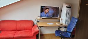 een kamer met een rode bank en een bureau met een tv bij Sehr gemütliches und gepflegtes Zimmer 8 Km von Bern-City in Köniz