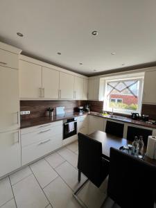 a kitchen with white cabinets and a table and a window at Ferienwohnung Aspelohe - Apartment 2 in Norderstedt