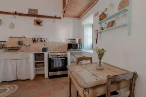 LIKE-HOME-Kina House-Casa do Lagar-Ericeira في مافرا: مطبخ مع طاولة وموقد فرن علوي
