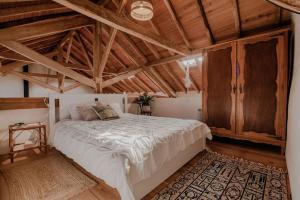LIKE-HOME-Kina House-Casa do Lagar-Ericeira في مافرا: غرفة نوم بسرير كبير في غرفة بسقوف خشبية