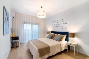 a bedroom with a bed with a writing on the wall at Apartamento Beira Mar - 2º Esquerdo in Tavira