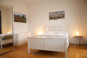 a bedroom with a white bed and a mirror at Strandvogtei Sellin - FeWo 5 - sehr zentrales großes Apartment in Ostseebad Sellin +5 photos