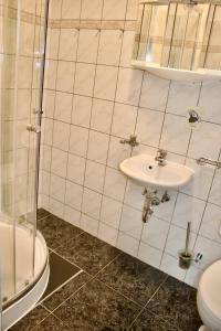 a white tiled bathroom with a sink and a shower at Strandvogtei Sellin - FeWo 5 - sehr zentrales großes Apartment in Ostseebad Sellin