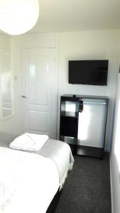 New & delightful 3 bed house in East Kilbride في غلاسكو: غرفة نوم بسرير وتلفزيون بشاشة مسطحة
