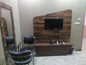 una stanza con due sedie e una televisione su una parete di Hotel Pearl Grand Prime a Karnal