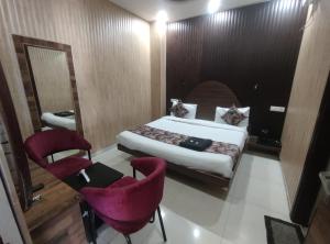 a hotel room with a bed and two chairs at Hotel Pearl Grand Prime in Karnal