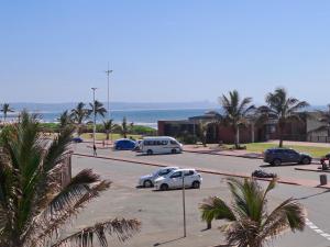 - un parking avec des voitures, des palmiers et l'océan dans l'établissement Unit 103 Tenbury, à Durban