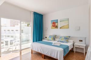 a white bedroom with a bed and a balcony at Hostal Neptuno in Paguera