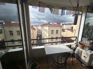 a balcony with a table and a view of a city at Appartement familial avec balcon et parking in Lyon