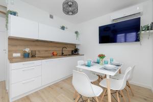 a kitchen with white cabinets and a white table and chairs at Apartment with Garden 450 m to the Beach by Rent like home in Dziwnówek