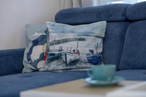 a blue couch with a pillow with a picture of a boat at Apartment with Garden 450 m to the Beach by Rent like home in Dziwnówek