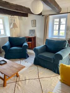 una sala de estar con 2 sofás azules y una mesa. en Une Chaumière à Port Manech', en Névez
