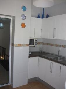 - une cuisine blanche avec évier et four micro-ondes dans l'établissement APARTAMENTO SEVILLA, à Alcalá de Guadaira